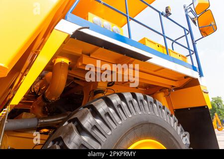 Enormi ruote posteriori del dumper a cassone ribaltabile con angolazione insolita in primo piano. Le ruote sono dotate di un battistrada per il movimento del dumper su terreni sfusi. Foto Stock