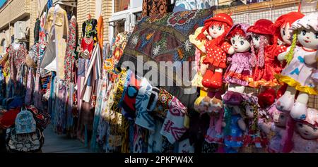 Tradizionale negozio di souvenir che vende tessuti colorati, sciarpe e bambola in Uzbekistan Foto Stock