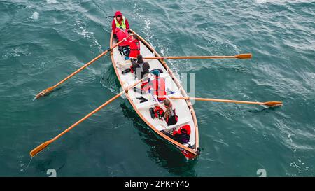 I vogatori su una tradizionale barca a remi in legno partecipano a una gara. Foto Stock