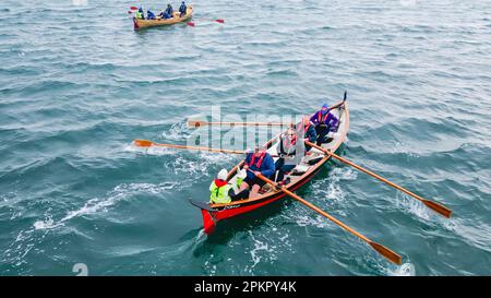 I vogatori su una tradizionale barca a remi in legno partecipano a una gara. Foto Stock