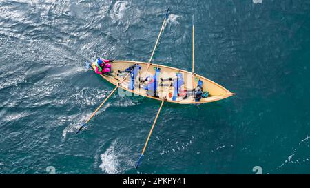 I vogatori su una tradizionale barca a remi in legno partecipano a una gara. Foto Stock