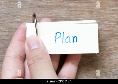 Scheda flash di tenuta della mano con scrittura a mano nella pianta di parola su fondo di legno Foto Stock