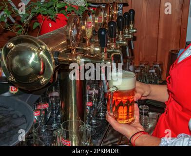 Slovacchia, Bratislava - 01.07.2023: Mani barman femmina che versano birra scura dal rubinetto in bar. Foto Stock