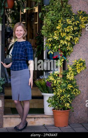 Una donna si trova all'ingresso di un negozio di fiori. Foto Stock