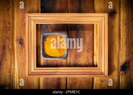 Polvere di curcuma in tazza, su fondo di legno Foto Stock