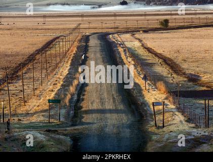 La prima luce dell'alba colpisce una strada di campagna che conduce al villaggio di Cydarville nella Provincia del Capo Orientale del Sud Africa. Foto Stock