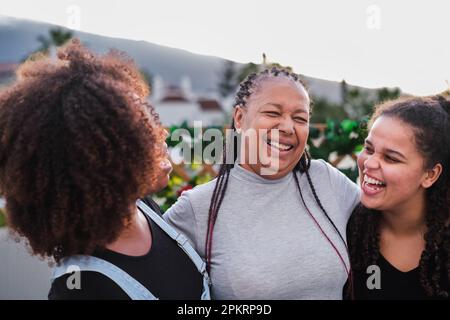 Madre che ha un momento divertente e ridendo con le sue figlie ad un pasto di famiglia all'aperto. Concetto: Tempo di qualità, famiglia, divertimento Foto Stock