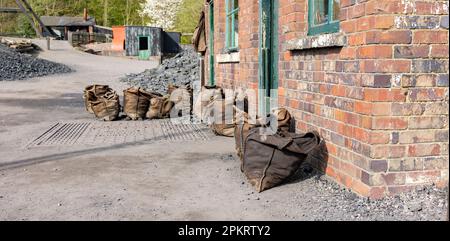 Un cantiere di carbone del 1900 e un ponte pesante con sacchi di carbone all'esterno pronti per la vendita. Foto Stock
