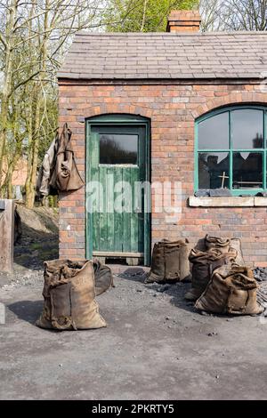 Un cantiere di carbone del 1900 e un ponte pesante con sacchi di carbone all'esterno pronti per la vendita. Foto Stock