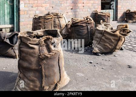 Un cantiere di carbone del 1900 e un ponte pesante con sacchi di carbone all'esterno pronti per la vendita. Foto Stock