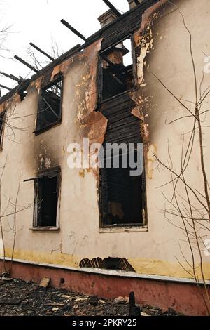 Facciata di una vecchia casa a due piani dopo un incendio. Edificio residenziale bruciato. Esterno della casa distrutta. Foto Stock