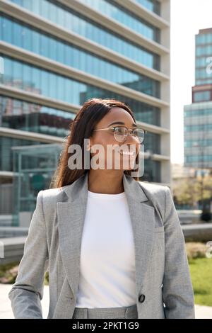 Donna professionale nera sorridente in piedi in ufficio all'aperto. Foto Stock