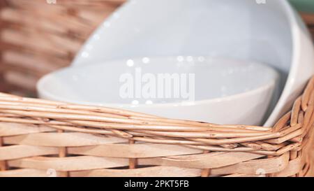 Stoviglie da tavola in ceramica bianca pulita in un cestino, stile rustico Foto Stock