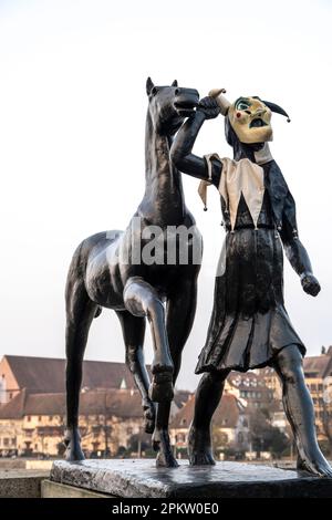 Amazon guida una scultura a cavallo di Carl Burckhardt sul ponte Mittlere Brucke durante il Carnevale con una maschera Foto Stock