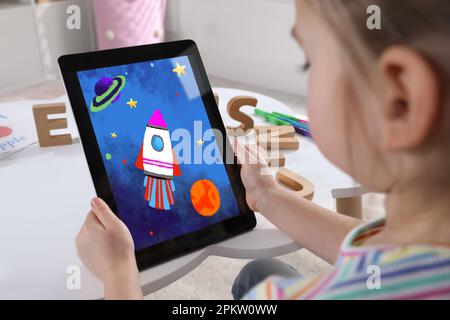 Bambina che tiene un tablet con un disegno carino a casa. Arte per bambini Foto Stock
