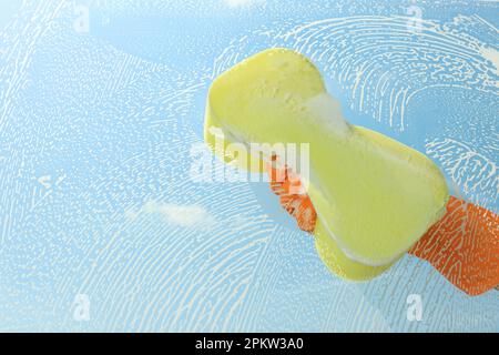 Persona che pulisce il vetro con la spugna, vista dall'interno Foto Stock