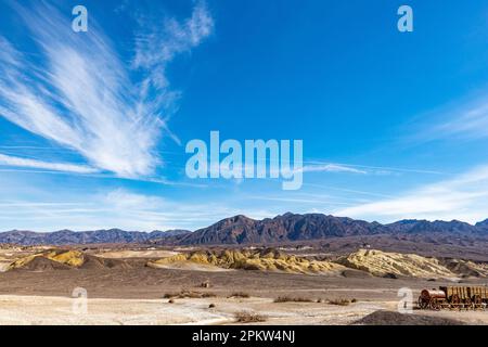 Death Valley CA USA - Feb 17 2023: Vista delle montagne del deserto e Twenty Mule Team Wagon in mostra presso le opere di borace Harmony Foto Stock