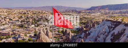 BANNER, GRANDE FORMATO bandiera turca sulla collina con tipiche formazioni rocciose di tufo della Cappadocia sullo sfondo di un cielo blu, Goreme, Turchia Foto Stock