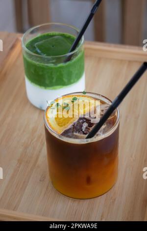 Matcha greentea ghiacciata e caffè nero arancio ghiacciato su tavolo di legno, foto di scorta Foto Stock