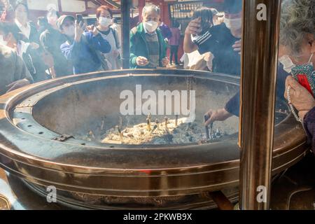 Tokyo, Giappone - 20 marzo 2023: Un gruppo di persone che inalano il fumo di incenso al tempio buddista senso-ji situato nel quartiere di Asakusa Foto Stock