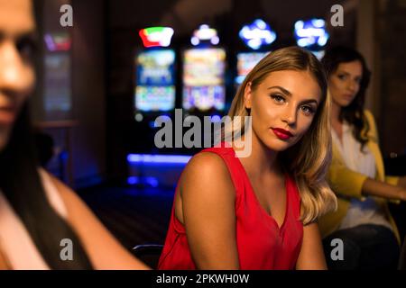 Giovani Donne di notte alla macchina automatica in un casinò e celebrare Foto Stock