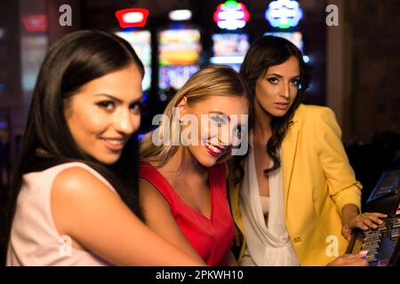 Giovani Donne di notte alla macchina automatica in un casinò e celebrare Foto Stock