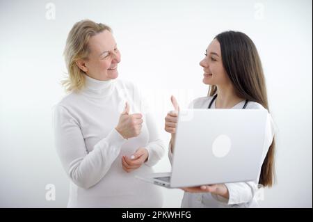 giovane donna paziente sul letto che mostra pollici con viso sorridente molto buon sintomo per la giovane donna asiatica medico in background ospedaliero. Foto di alta qualità Foto Stock