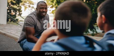 Insegnante che dà ai suoi studenti un pep talk nella scuola elementare. Educatore maschile motivando un gruppo di bambini prima della classe. Tutoraggio e guida in pri Foto Stock