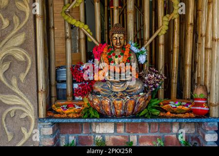 Statua di buddha di bronzo seduta in meditazione con decorazioni floreali per la cerimonia del festival. Foto di alta qualità Foto Stock