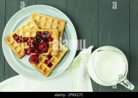 Waffle belgi freschi con frutta, vista dall'alto. Colazione gustosa. Waffle fatti in casa con fragole, zucchero a velo su un piatto, su uno sfondo di legno. S Foto Stock