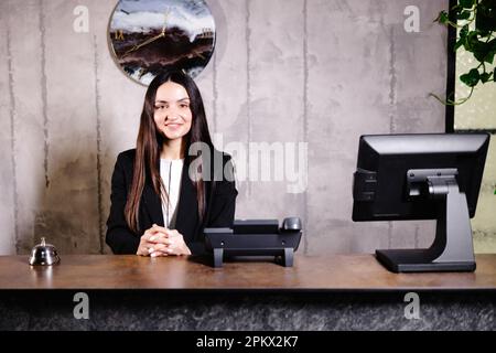 Ritratto dell'addetto alla reception al banco nella lobby. Design del banner. Concierge cordiale alla reception dell'hotel dietro il banco Foto Stock