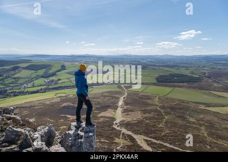 Uomo escursionista in piedi sulla roccia ammirando il paesaggio montano di wicklow Foto Stock