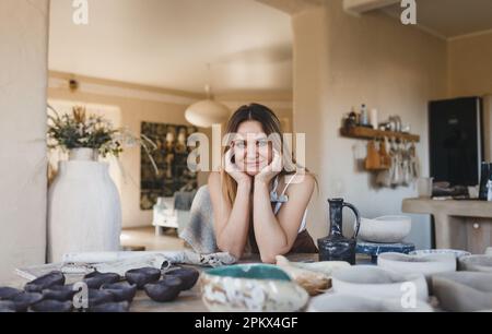 ritratto di una ragazza ceramista seduta a un tavolo Foto Stock