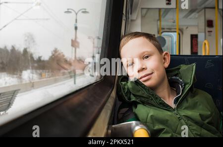 ragazzo seduto su un sentiero sorridente mentre si va a scuola Foto Stock