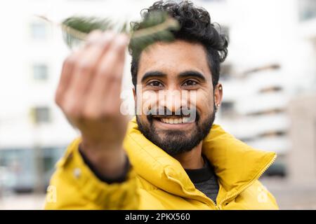 Giovane uomo che tiene una scottatura verde nella mano fuori Foto Stock