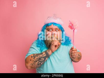 L'uomo serio grasso con i tatuaggi agisce come una fata magica Foto Stock