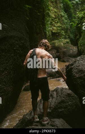 Un giovane viaggia attraverso le giungle tropicali di Bali. Foto Stock