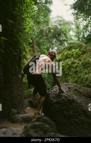 Un giovane viaggia attraverso le giungle tropicali di Bali. Foto Stock