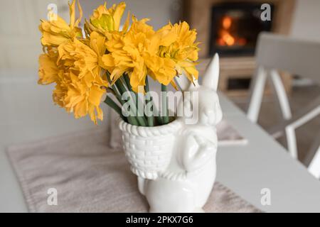 Bouquet di narcisi in vaso a forma di lepre, composizione pasquale. Foto Stock