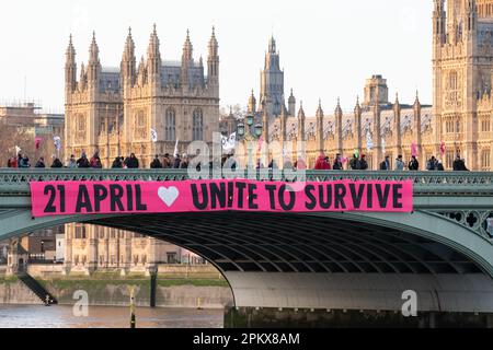 Gli attivisti della ribellione Extinction eseguono un banner drop su Westminster Bridge dichiarando "Unite per sopravvivere", pubblicizzando le future proteste climatiche. Foto Stock