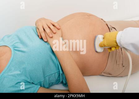 Donna incinta durante la procedura di screening della gravidanza con sonogramma nel centro perinatale, primo piano. Screening prenatale e analisi Foto Stock