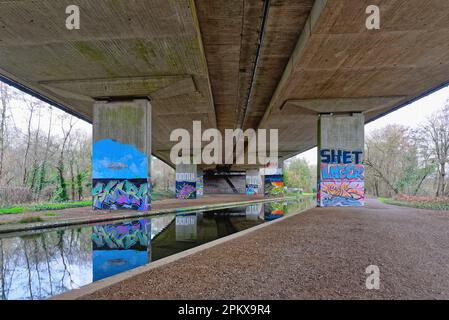 Graffiti dipinti su colonne che sostengono il ponte del M25 che lo porta sul canale River Wey a New Haw Surrey Inghilterra UK Foto Stock