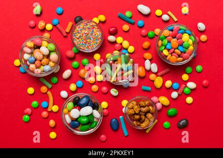 caramelle tonde di colore diverso in ciotola e vasetti. Vista dall'alto di una grande varietà di dolci e caramelle con spazio copia. Foto Stock