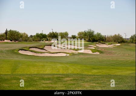 Un paesaggio panoramico caratterizzato da un lussureggiante campo da golf con bunker di sabbia sparsi attraverso il fairway e alberi alti Foto Stock