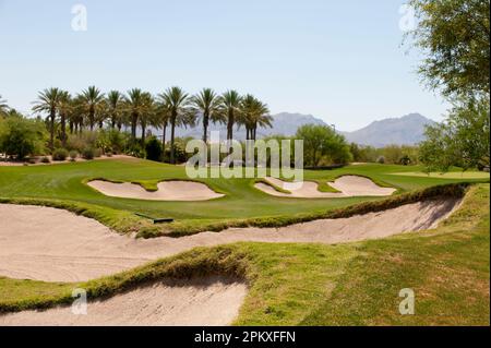 Un paesaggio panoramico caratterizzato da un lussureggiante campo da golf con bunker di sabbia sparsi attraverso il fairway e alberi alti Foto Stock