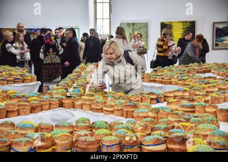 Lviv, Ucraina. 08th Apr, 2023. Una donna scatta una foto del Tridente dell'Ucraina da mille dolci pasquali sul suo cellulare. A Lviv, è stato stabilito un nuovo record ucraino - in 25 minuti e 17 secondi, la gente ha decorato 1.000 torte di Pasqua e li ha disposti a forma di tridente. Questo è il più grande tridente ucraino mai fatto da dolci di Pasqua. Tutte le torte di Pasqua saranno vendute, e i proventi saranno utilizzati per acquistare droni per l'esercito ucraino. (Foto di Pavlo Palamarchuk/SOPA Images/Sipa USA) Credit: Sipa USA/Alamy Live News Foto Stock