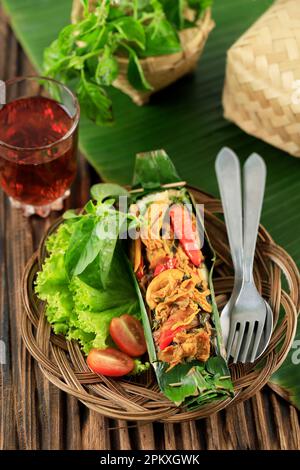Nasi Bakar Ayam Suwir Kemangi, riso al vapore con pollo tritato speziato Stir Fry e foglia di basilico dolce, avvolgimento con foglia di banana e grigliata Foto Stock