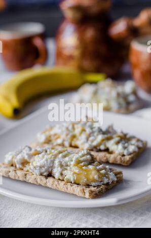 Panino con formaggio di ricotta, miele e banana su un pane dietetico. Mangiare sano Foto Stock