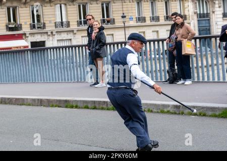 Spettacolo senza tempo: Un uomo di 60 anni con un abbigliamento anni '1940 esegue impressionanti trucchi Roller Blade su un ponte parigino, catturando gli spettatori Foto Stock