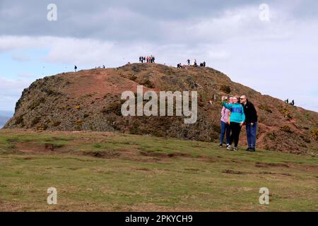 Edimburgo, Scozia, Regno Unito. 10th aprile 2023. Forti venti sulla cima di Arthur's Seat non sembrano scoraggiare le orde dei turisti del lunedì di Pasqua, con belle vedute tutto intorno nel pomeriggio parzialmente soleggiato. Parlare di un selfie di gruppo sulla strada per Arthurs Seat vertice. Credit: Craig Brown/Alamy Live News Foto Stock